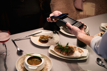 Two people making contactless payment in restaurant at evening