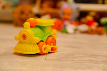 Fototapeta premium Small plastic toy train on floor. Colorful toddler engine model for imaginative play. Childhood development object for nursery school and home activity. Cute miniature transport vehicle.