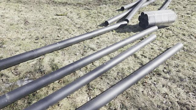 Plastic pipes prepared for underground installation at urban construction site with soil excavation. Infrastructure repair concept with pipeline installation for water supply, sewage or drainage syste
