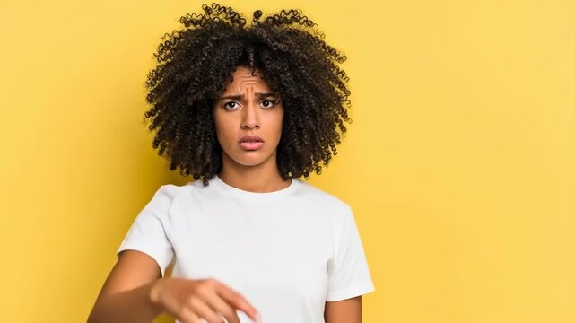 A young woman pointing accusingly against a bright yellow background