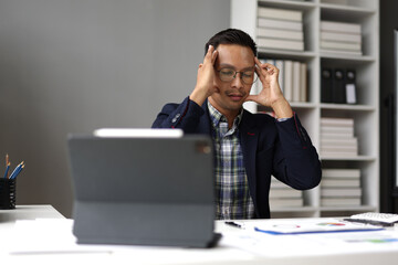Stressed businessman looking at financial reports in office.