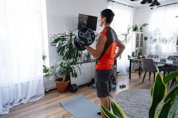 Man in orange sports shirt, home workout, strength training with dumbbells, minimal decor, plants, window, home gym routine, modern fit lifestyle