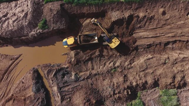 gr&uacute;a  excavadora descarga sobre el dumper mientras se revela el impacto ambiental de la cantera