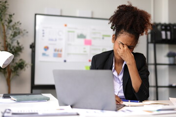 Stressed manager suffering from headache working on laptop in office.