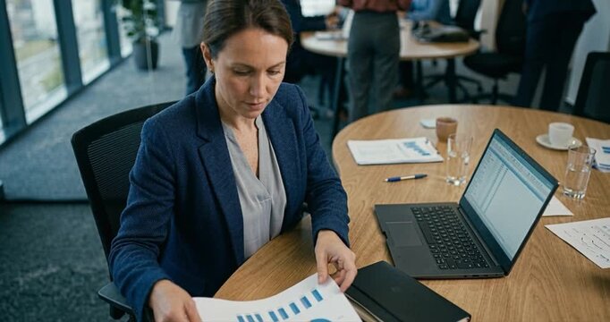 Woman reviews documents at desk meeting preparation indoors