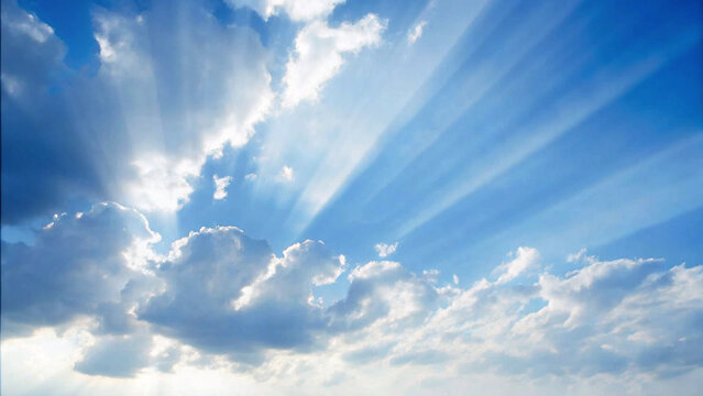 Dramatic blue sky with sun rays shining through fluffy white clouds