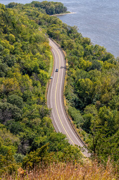 Winding Great River Road (Highway 35) along Maiden Rock Bluff, Wisconsin, with green forest, river, sandy bend, and scenic natural landscape.