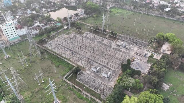 Aerial view of a high-voltage electrical substation showing power lines, transformers, and switchgears for electricity generation and distribution in an urban area