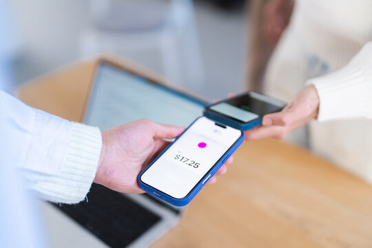 A person makes a contactless payment using a mobile device, tapping it against another device to complete a transaction of seventeen dollars and twenty-five cents.