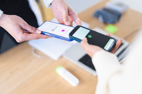 Two people are using their mobile phones to make a payment. One phone displays a transaction amount of $17.25.