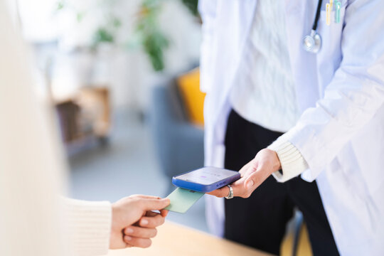A patient pays for medical services using a credit card and a mobile device at a doctor's office.