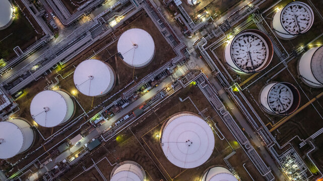 Aerial view industrial storage tank oil and gas chemical, Global fuel supply oil and gas, Industrial oil and gas storage tank farm facility energy reserve infrastructure fuel supply chain at night.