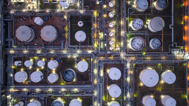 Aerial view industrial storage tank oil and gas chemical, Global fuel supply oil and gas, Industrial oil and gas storage tank farm facility energy reserve infrastructure fuel supply chain at night.
