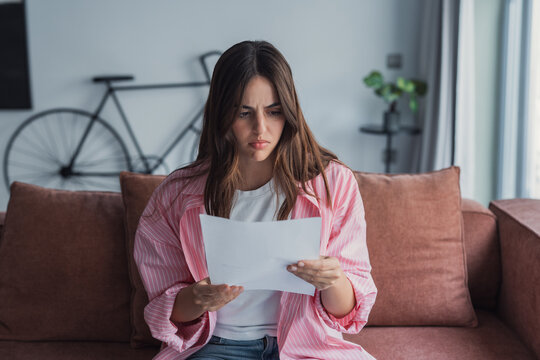 Worried young Caucasian woman indoor read post paper letter think of bad news or problem in notice, distressed millennial female frustrated confused by negative response in postal paperwork mail&nbsp;