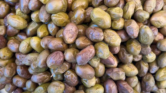 Nocellara olives of the Sicilian Etnea or Belice varieties, served crushed and viewed from above with a rotating camera shot