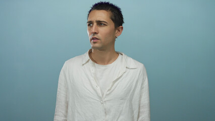 Obraz premium Young hispanic man in white shirt stands isolated against a blue background wall, expressing curiosity with a thoughtful pose and a pensive facial expression.