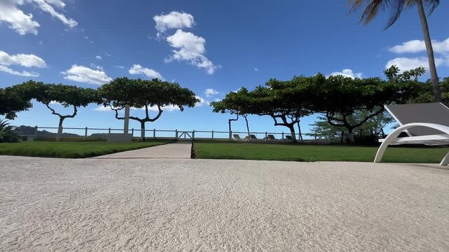 Pool deck low cinematic shot overlooking ocean front resort with palm trees and swimming pool home vacation rental.