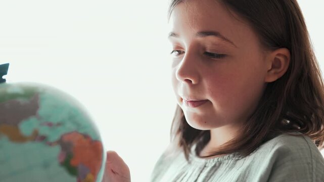 Little girl looking at globe and dreaming of travel, 4K 10-bit.	
