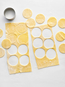 The image shows freshly rolled pasta dough with circular cutouts ready for filling. This visual is ideal for food blogs, recipe websites, and cooking classes