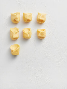 This image showcases fresh handmade tortellini arranged neatly on a white background. Ideal for use in restaurant menus, food blogs, and culinary advertising