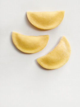 Three pieces of fresh pasta dough are displayed on a white background. This visual is ideal for recipe blogs, cooking tutorials, packaging designs, and social media content related to Italian cuisine