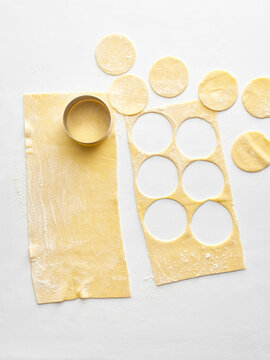 The image shows fresh pasta dough rolled out with circles cut out using a round cutter. Ideal for food blogs, cooking tutorials, restaurant menus, and social media content about homemade cuisine