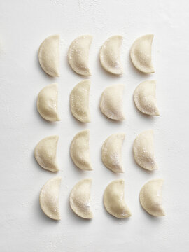 Dumplings are neatly arranged in rows on a light surface. This image is suitable for restaurant menus, cooking blogs, and food packaging