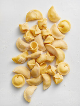 The image shows a variety of fresh handmade pasta shapes arranged on a light surface. This visual is ideal for restaurant menus, cooking tutorials, food blogs, and culinary advertising