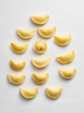 The photo shows a series of uncooked dumplings neatly arranged on a white surface. This image is ideal for restaurant menus, food blogs, social media posts, or cooking articles