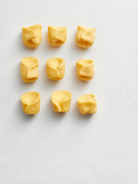 Nine pieces of handmade tortellini are arranged on a light background. This image is ideal for restaurant menus, food blogs, and social media posts about Italian cooking