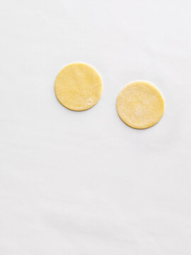 Two uncooked dough rounds are placed on a clean, white surface. Ideal for use in baking recipes, cooking blogs, restaurant menus, and culinary tutorials