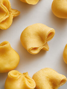 This image features various shapes of fresh pasta dough on a light background. Perfect for restaurant menus, food blogs, and social media posts showcasing Italian cuisine