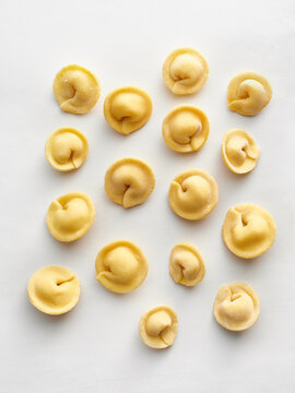 A display of freshly made tortellini pasta arranged on a white surface. This visual is perfect for restaurant menus, recipe blogs, or culinary advertising