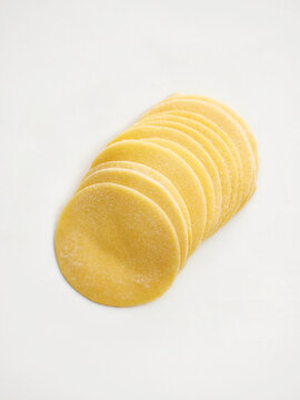 This image showcases neatly stacked fresh pasta dough rounds ready for cooking or filling. Ideal for use in restaurant menus, cooking blogs, and food packaging