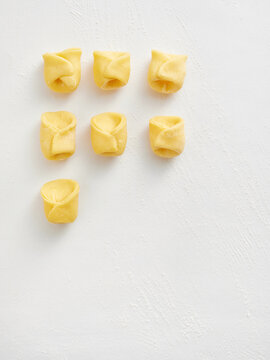 The image shows freshly shaped tortellini arranged in a grid on a clean white surface. This versatile dish is ideal for use in restaurant menus, food blogs, and culinary advertisements