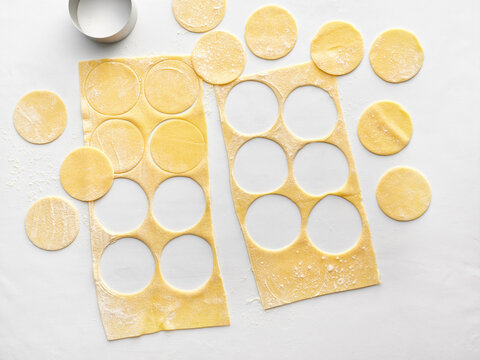 Freshly rolled pasta dough with round pasta shapes cut out using a cutter. Ideal for restaurant menus, cooking blogs, and culinary instructional content