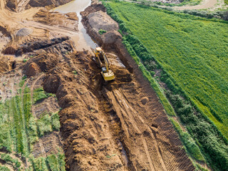 Aerial view of an excavator loading earth into a dumper truck during earthmoving works and industrial logistics. © Ivanb
