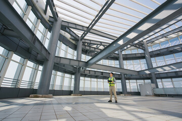 Engineer inspecting a modern steel and glass curtain wall building interior