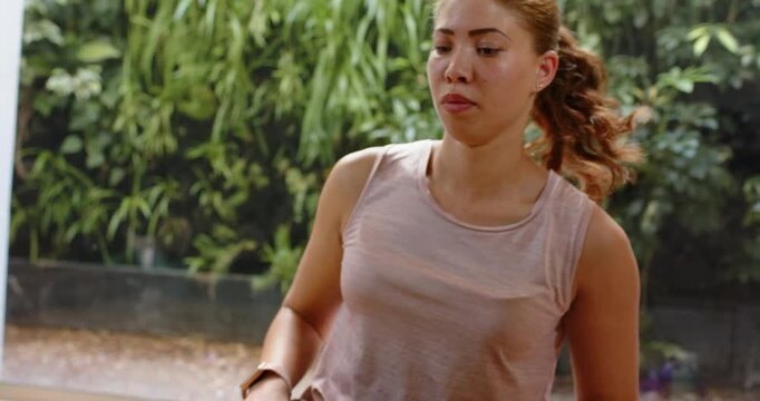 Woman adjusting knee on mat, shifting hips back folding toward toes for fitness, smartwatch visible