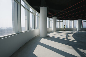 Naklejka premium Spacious office interior with abundant natural light and structural columns in an unfinished high-rise building
