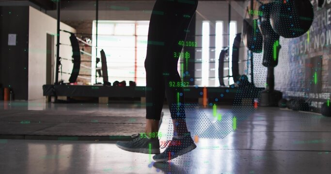 Balancing woman wearing black leggings and grey-green shoes on mats in gym, with chart overlays