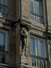 Obraz premium Detailed view of a historic Baroque church facade featuring twin towers with green copper roofs, classical stone statues of saints, and a shining gold cross against a clear blue sky in Lviv, Ukraine.