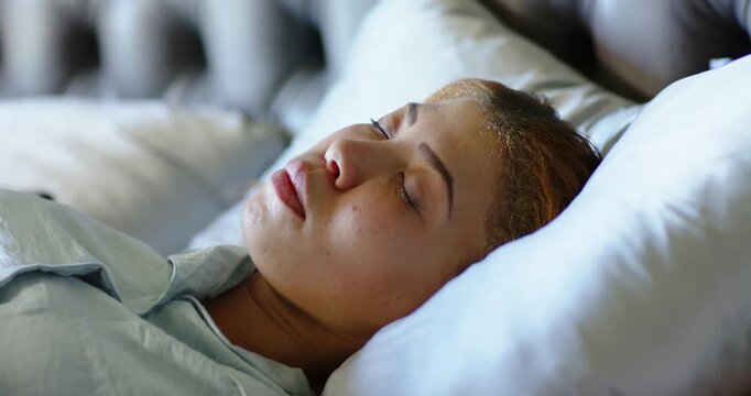 Woman is resting and breathing on bed, causing slight head tilts, pillow shifts, eyelid movements