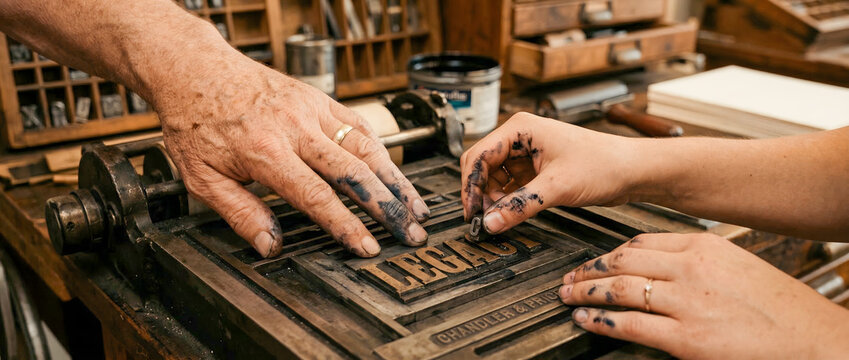 Close up of hands setting type for LEGACY on vintage letterpress machine in workshop