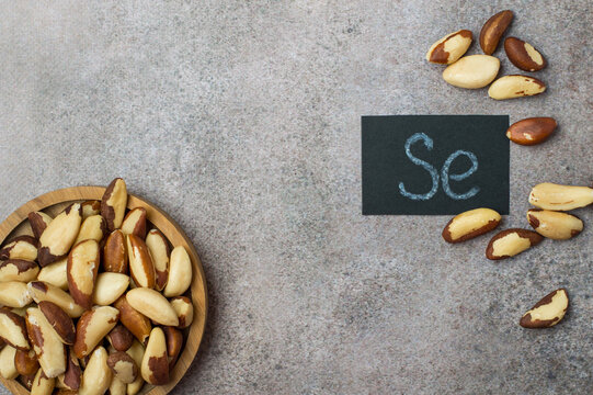 Brazil nuts on a gray background with the chemical symbol for selenium (Se). A natural source of minerals for thyroid health, antioxidant support, and metabolic health.  space for text.