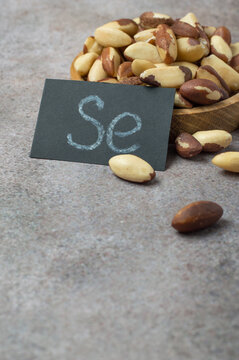 Brazil nuts in a wooden bowl with a card showing the chemical symbol for selenium (Se) and blank space. A natural, organic source of minerals for thyroid health and antioxidant support.
