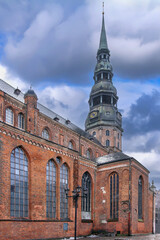 Obraz premium Side and rear view of St Peters Church in Old Town, Riga, Latvia. Historic Gothic architecture and red brick walls