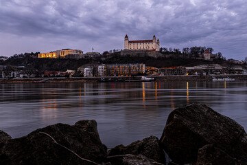 Obraz premium Bratislava Castle at dusk above the Danube with city lights in Slovakia