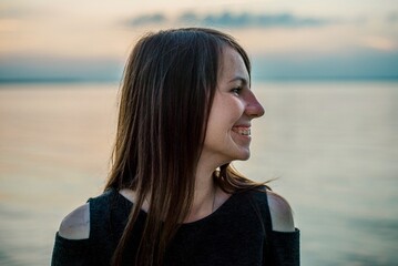 Side profile portrait of smiling young woman near lake at sunset © Bohdan