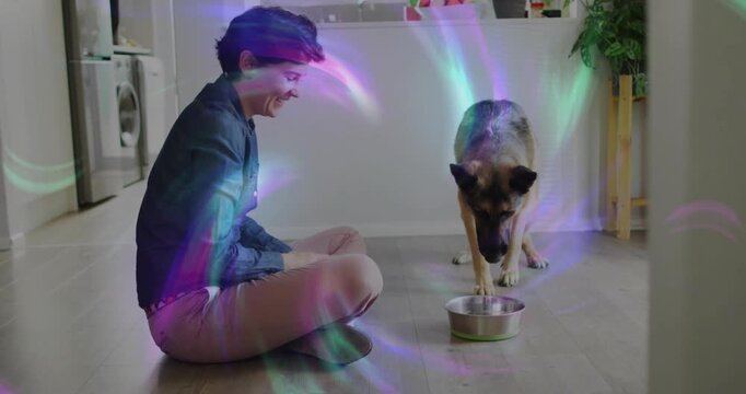 Vertical video: Woman placing metal bowl in kitchen urging dog eating, petcare overlay obscuring
